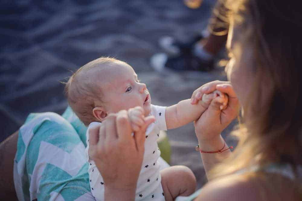mom holdling her baby on her lap at the beach